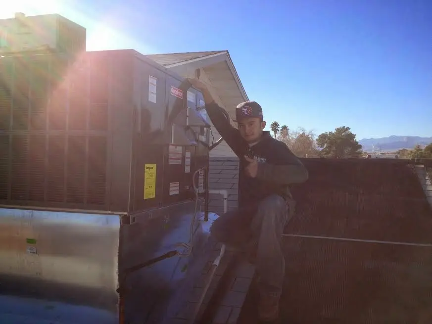 HVAC technician performing Air Duct Cleaning on a rooftop unit in Lapeer