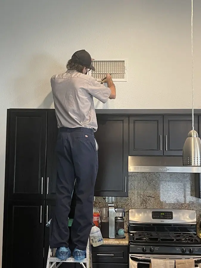 Technician inspecting an air vent during HVAC service in Lapeer